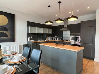 a kitchen with black cabinets and a table with chairs at Stunning Apartment at Glasgow Hydro & SECC - Glasg in Glasgow