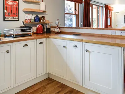 a kitchen with white cabinets and wood floors at Oakwood Cottage - Glencoe in Glencoe