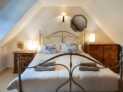 a bedroom with a bed and a mirror on the wall at Oakwood Cottage - Glencoe in Glencoe
