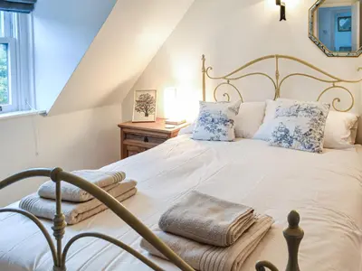 a bedroom with a large white bed with blue pillows at Oakwood Cottage - Glencoe in Glencoe