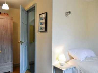 a bedroom with a bed and a lamp on a table at Oakwood Cottage - Glencoe in Glencoe
