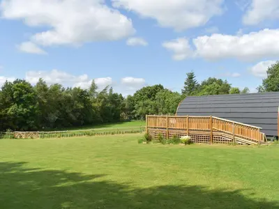 a field with a fence and a barn at Pentland Pod - Cottage in Penicuik