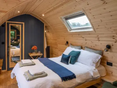 a bedroom with a large bed in a log cabin at Pentland Pod - Cottage in Penicuik