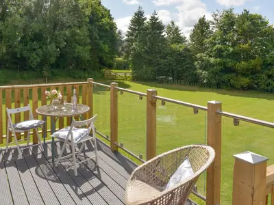 a wooden deck with a table and chairs on it at Pentland Pod - Cottage in Penicuik