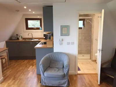 a living room with a chair and a kitchen at Ledi - Cottage in Linlithgow