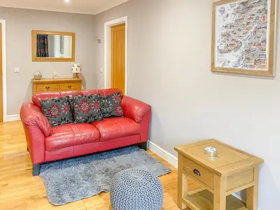 a red leather couch in a living room with a table at Dalnafeidh Beag - Cottage in Portnacroish