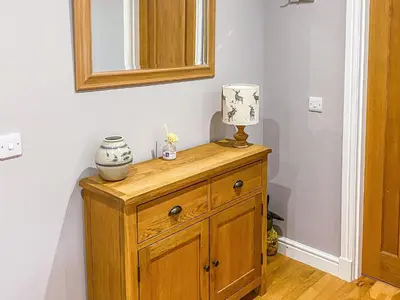 a wooden dresser with a mirror and a lamp on it at Dalnafeidh Beag - Cottage in Portnacroish