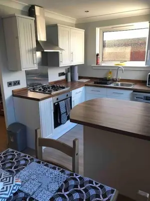a kitchen with white cabinets and a wooden counter top at Cosy Home with Free Parking Near Edinburgh St Andrews M90 & Amazon in Dunfermline