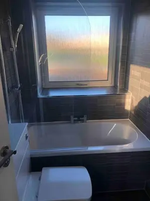 a bathroom with a tub with a window and a toilet at Cosy Home with Free Parking Near Edinburgh St Andrews M90 & Amazon in Dunfermline