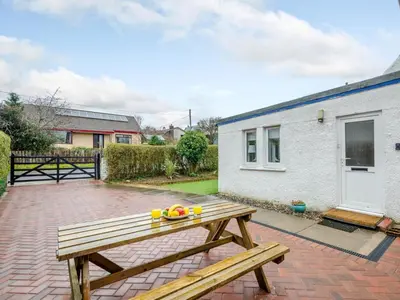 a wooden picnic table sitting on a brick patio at Cosy 3 bedroom home in centre of Brodick in Brodick