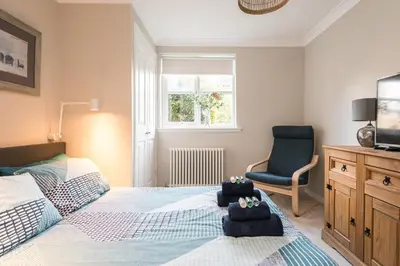a bedroom with a bed and a chair and a television at Cosy Roseburn Apartment, Edinburgh - 2 Bedrooms, FREE PARKING in Edinburgh