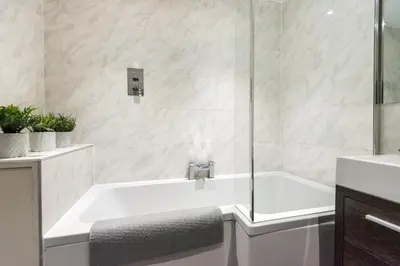 a white bathroom with a tub and a sink at Cosy Roseburn Apartment, Edinburgh - 2 Bedrooms, FREE PARKING in Edinburgh