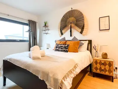 a bedroom with a bed with a large fan on the wall at Lovely 2 Bed Duplex Apartment with Hydro Views in Glasgow