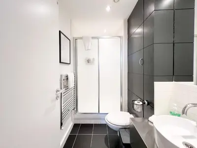 a bathroom with a toilet and two sinks and a window at Lovely 2 Bed Duplex Apartment with Hydro Views in Glasgow