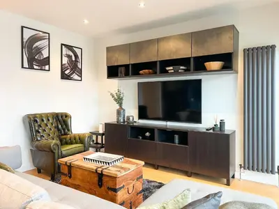 a living room with a flat screen tv and a couch at Lovely 2 Bed Duplex Apartment with Hydro Views in Glasgow