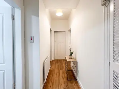 a hallway with white walls and wood floors at Attractive 3 Bedroom Apartment in Polmadie