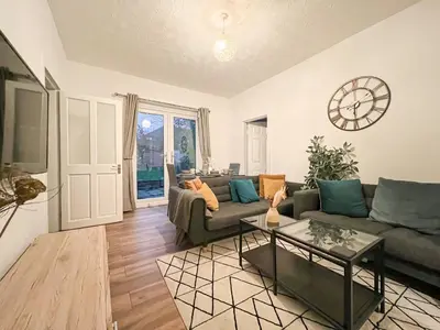 a living room with a couch and a clock on the wall at Attractive 3 Bedroom Apartment in Polmadie