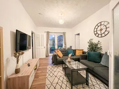 a living room with a couch and a clock on the wall at Attractive 3 Bedroom Apartment in Polmadie