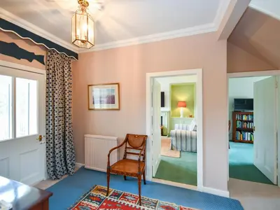 a room with a chair and a bedroom at Pinclanty Cottage in Pinmore