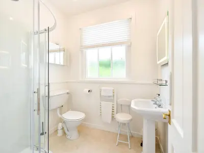a white bathroom with a toilet and a sink at Pinclanty Cottage in Pinmore