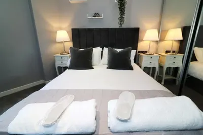 a bedroom with a large white bed with two white towels at Glas Go Executive 2-Bedroom Apartment near OVO Hydro Free Parking in Glasgow