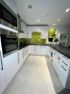 a kitchen with white cabinets and a washer and dryer at Glas Go Executive 2-Bedroom Apartment near OVO Hydro Free Parking in Glasgow