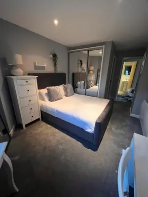 a bedroom with a bed and a dresser and a mirror at Glas Go Executive 2-Bedroom Apartment near OVO Hydro Free Parking in Glasgow