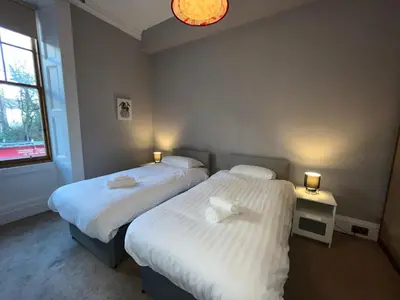 two beds in a room with two lamps on them at Bright 3 Bedroom Edinburgh City Apt in Edinburgh