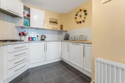 a kitchen with white cabinets and a tile floor at Modern 1BR flat - free parking + lift in Edinburgh