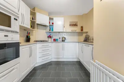 a white kitchen with white cabinets and a tile floor at Modern 1BR flat - free parking + lift in Edinburgh