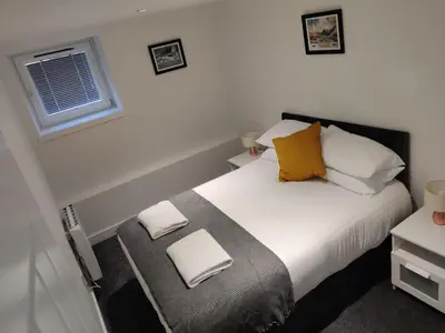 a bedroom with a bed with yellow pillows and a window at No 7 Westbay Apartment in Oban