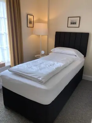 a bedroom with a large bed with white sheets at Glenheurie Cottage in Polmood