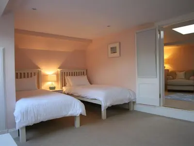 a bedroom with two beds and a mirror at The Coach House at Stewart Hall in Rothesay