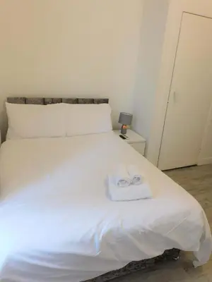 a bedroom with a white bed with two towels on it at Comfortable 4 bed Apt in Paisley Next to Station in Paisley