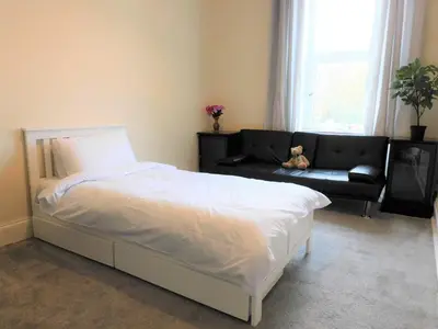 a bedroom with a bed and a couch and a teddy bear at Comfortable 4 bed Apt in Paisley Next to Station in Paisley