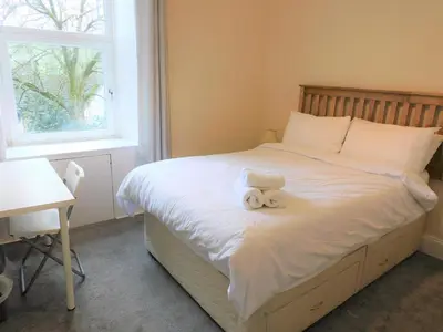 a bedroom with a bed with a teddy bear on it at Comfortable 4 bed Apt in Paisley Next to Station in Paisley