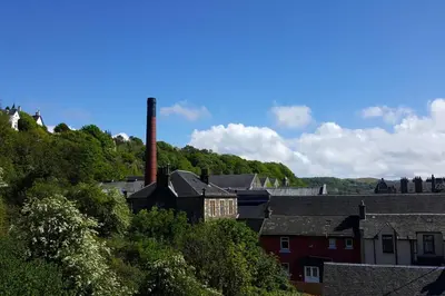 a group of buildings with a chimney and trees at The Distillers Den in Oban
