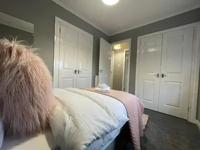 a bedroom with a bed with a pink blanket at Dunbeth House in Coatbridge