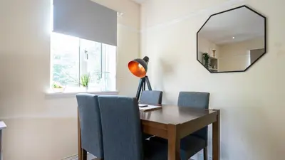 a dining room table with blue chairs and a mirror at The Riverside in Alloa
