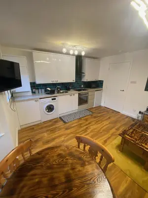 a kitchen with white cabinets and a wooden floor at cosy 1 bed flat Largs in Largs