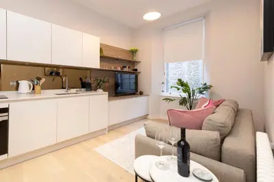 a kitchen and living room with a couch and a table at JOIVY Tasteful Studios on Rose South in Edinburgh