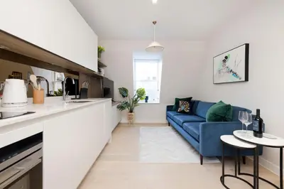 a living room with a blue couch and a kitchen at JOIVY Tasteful Studios on Rose South in Edinburgh