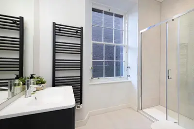 a white bathroom with a shower and a sink and a toilet at JOIVY Tasteful Studios on Rose South in Edinburgh