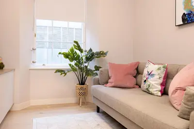 a living room with a couch with pillows and a plant at JOIVY Tasteful Studios on Rose South in Edinburgh