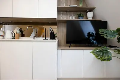 a kitchen with white cabinets and a flat screen tv at JOIVY Tasteful Studios on Rose South in Edinburgh