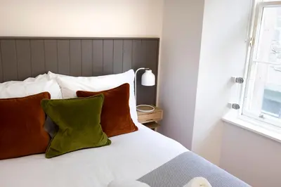a bedroom with a bed with two pillows and a window at JOIVY Tasteful Studios on Rose South in Edinburgh