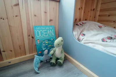 a book and two stuffed animals sitting next to a bed at Glamping Pods in Milngavie