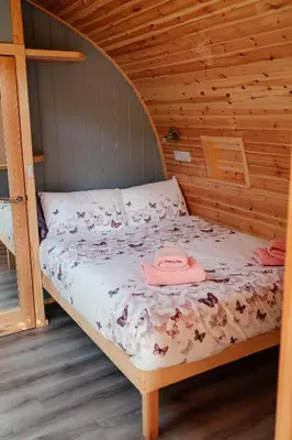 a bed in a wooden cabin with two towels on it at Glamping Pods in Milngavie
