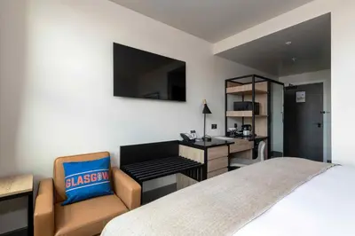 a bedroom with a desk and a bed with a chair at Sandman Signature Glasgow Hotel in Glasgow