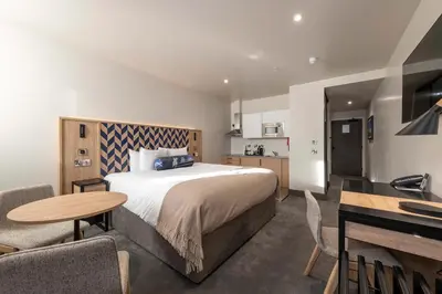 a hotel room with a bed and a table and chairs at Sandman Signature Glasgow Hotel in Glasgow